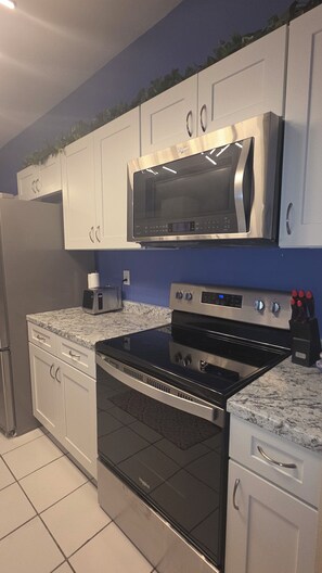 A kitchen with white cabinets, a stainless steel microwave, a black oven, and a granite countertop.
