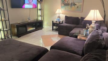A living room with a television, a painting, a lamp, and a ceiling fan.