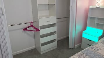 A bedroom with a bed, a closet with open doors, a dresser, and a nightstand.
