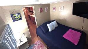 A bedroom with a bed, a TV, and a small kitchenette. - Anchor’s Rest at Swann’s Marina
Comfort • Hot Tub • Fire Pit • Pet Friendly (Dandridge)