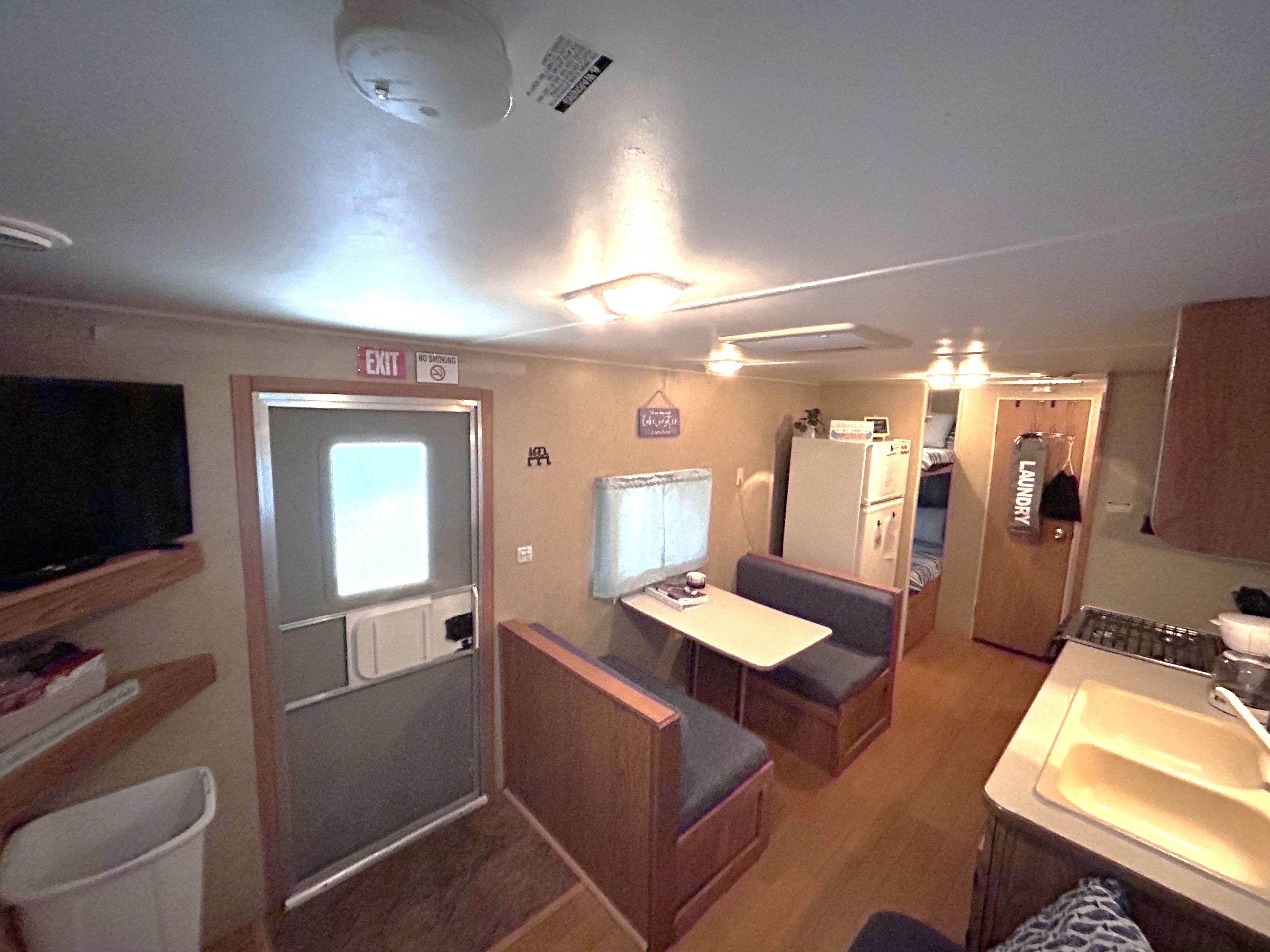 A compact RV interior with a kitchenette, a dining area, and a bathroom.