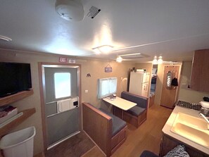 A compact RV interior with a kitchenette, a dining area, and a bathroom.