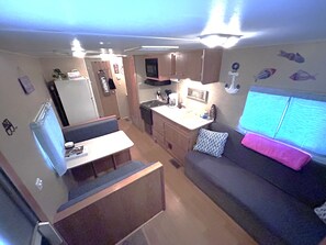 Interior de uma motorhome compacta, com cozinha compacta, área de estar e televisão.