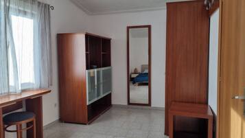 Ein Zimmer mit Holztisch, Stuhl, Kleiderschrank und Spiegel.