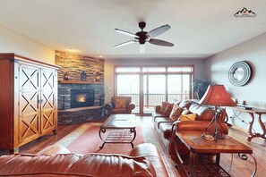 A spacious living room with a fireplace, leather sofa, and a dining area. - Luxury 2 Bedroom Condo with Long Range Views on Sugar Mountain (Sugar Mountain)