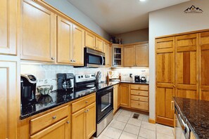 A kitchen with wooden cabinets, a microwave, a stove, and a coffee maker. - Luxury 2 Bedroom Condo with Long Range Views on Sugar Mountain (Sugar Mountain)