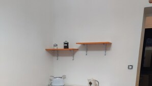 Una cocina pequeña con armarios color naranja, una encimera blanca y un piso con patrón hexagonal.