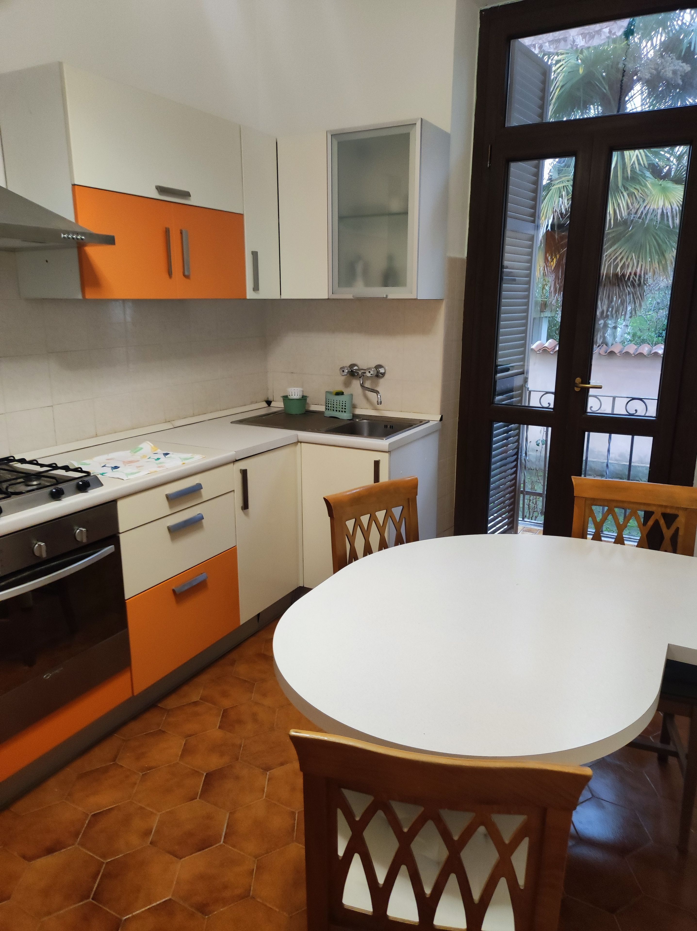 A kitchen with a stove, oven, and sink, and a dining area with a table and chairs.