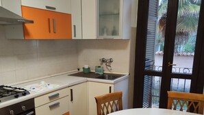 Una cocina con estufa, horno y lavabo, además de un comedor con mesa y sillas.