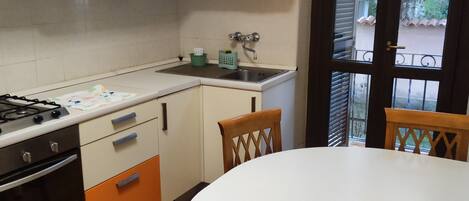 A kitchen with a stove, oven, and sink, and a dining area with a table and chairs.