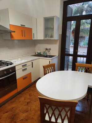 A kitchen with a stove, oven, and sink, and a dining area with a table and chairs. - 5 MINUTES FROM THE STATION AND DOWNTOWN (Alessandria)