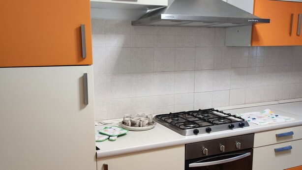 Una cocina con estufa a gas, horno y campana extractora.