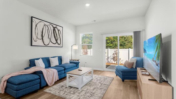 Een moderne woonkamer met een blauwe bank, een salontafel en een televisie op een houten dressoir.