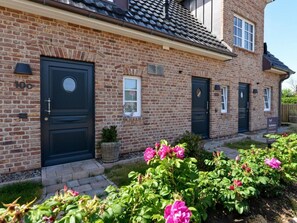 A brick house with two dark-colored doors, a small window, and a sign for Sotheby's. - Holiday Apartment in Sylt With 2 Bedrooms (Sylt)