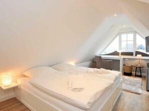 Ein Schlafzimmer mit einem Bett, Nachttischlampen, einem Schreibtisch und einem Fenster.