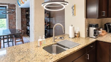 Eine moderne Küche mit Granit Arbeitsplatten, Edelstahlgeräten und dunklen Schränken.