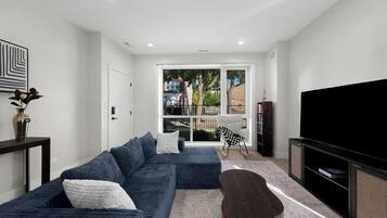 A modern living room with a sectional sofa, a television, and a view of the outside.