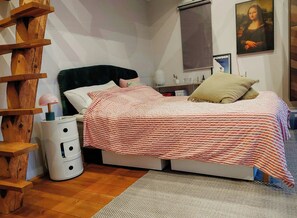 A bedroom with a bed, a nightstand, a lamp, a wooden ladder, and a painting on the wall. - Front-row seat to nature's spectacle (Lönsboda)