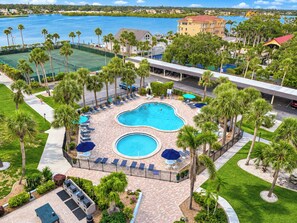 A resort with a central swimming pool surrounded by lounge chairs and palm trees. - Renovated + New Furniture, Bayfront Resort Class Amenities, Walk to Siesta Beach (Siesta Key)