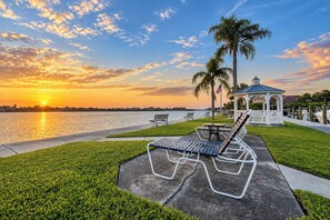 Un parc au bord de l’eau, doté d’un kiosque, de bancs et offrant une vue sur le coucher de soleil.