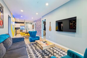 Uma sala de estar moderna com sofá, mesa de centro e televisão na parede.