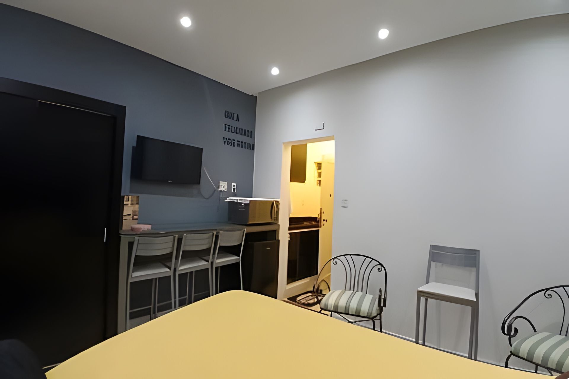 A small, modern room with a bed, a desk, and two chairs.