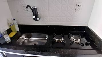 Une cuisine dotée d’un plan de travail noir, d’un évier en acier inoxydable et d’une cuisinière à gaz.