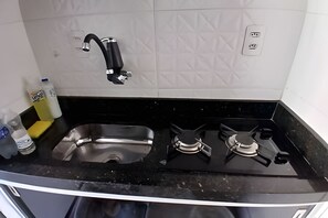 Una cocina con encimera negra, pileta de acero inoxidable y cocina a gas.