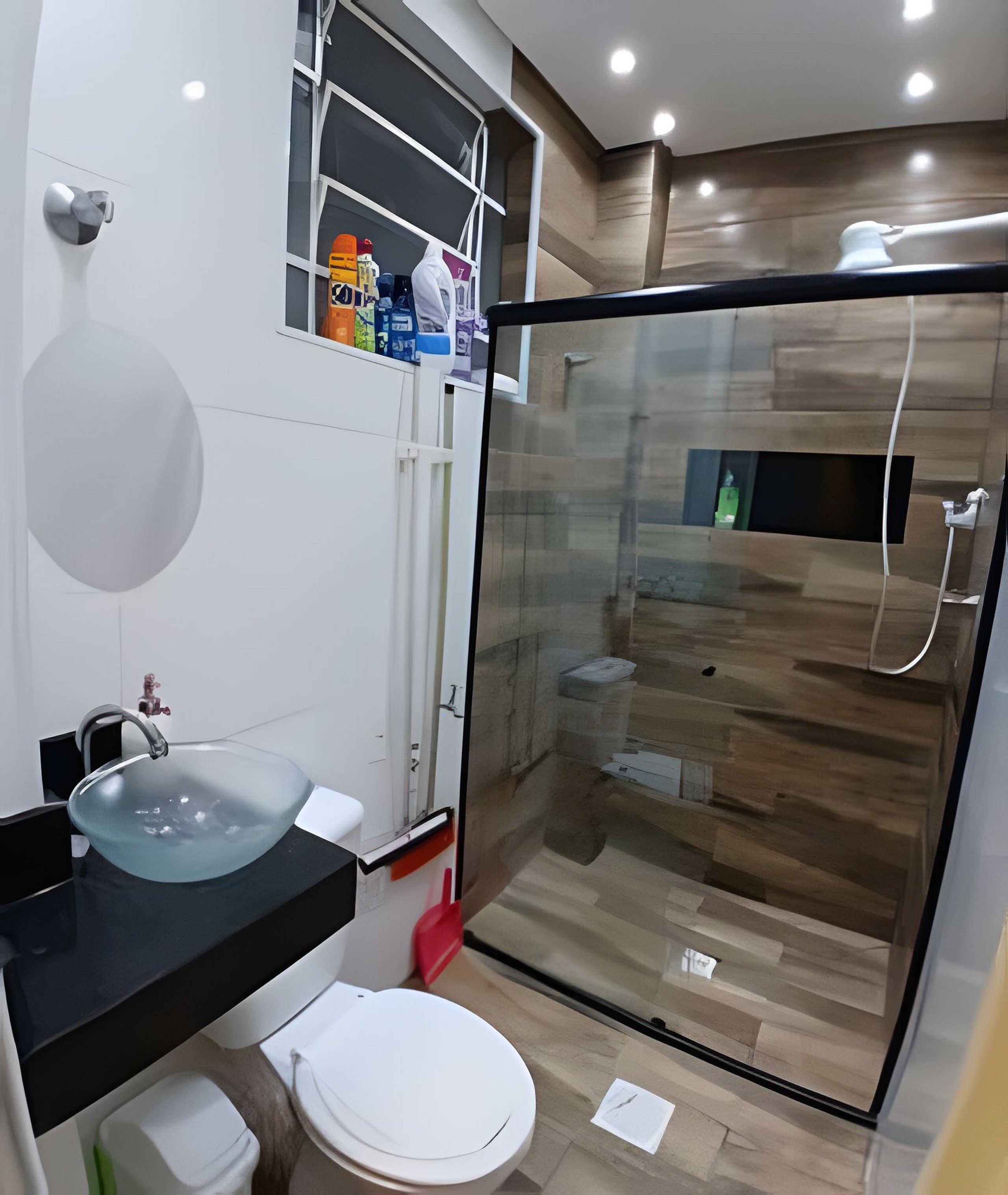 Un baño moderno con cabina de ducha de vidrio, lavamanos con encimera negra y un inodoro blanco.