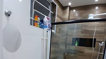 Un baño moderno con cabina de ducha de vidrio, lavamanos con encimera negra y un inodoro blanco.
