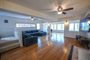 A spacious living room with a large sectional sofa, a ceiling fan, and a flat-screen TV. - Cozy Lake House on Lake Erie (Bay Village)