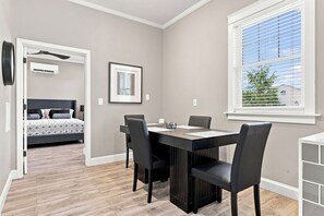 Una habitación con una mesa de comedor, sillas, una cama y una ventana con persianas.