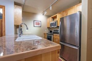 A kitchen with a stainless steel refrigerator, a microwave, an oven, a sink, and wooden cabinets. - Beautiful Teton Creek Resort Condo below Grand Targhee Resort and in Driggs ID (Driggs)