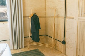 A corner room with a wooden drying rack, a window with curtains, and a wooden floor. - Cobalt Cabin by Homestead Modern (Yucca Valley)
