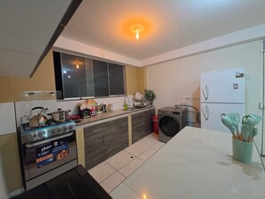 A modern kitchen with a gas stove, oven, and a built-in washing machine. - Moderno Depa Familiar de 3BR con Garaje Cerca a San Blas (Cusco)