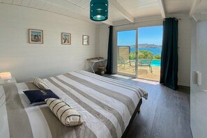 Ein Schlafzimmer mit Bett, Schreibtisch und Blick ins Freie.
