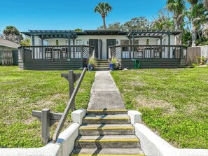 A pathway leading to a building with a porch and steps.