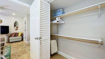 A walk-in closet with open doors, shelves, and a hanging rod.