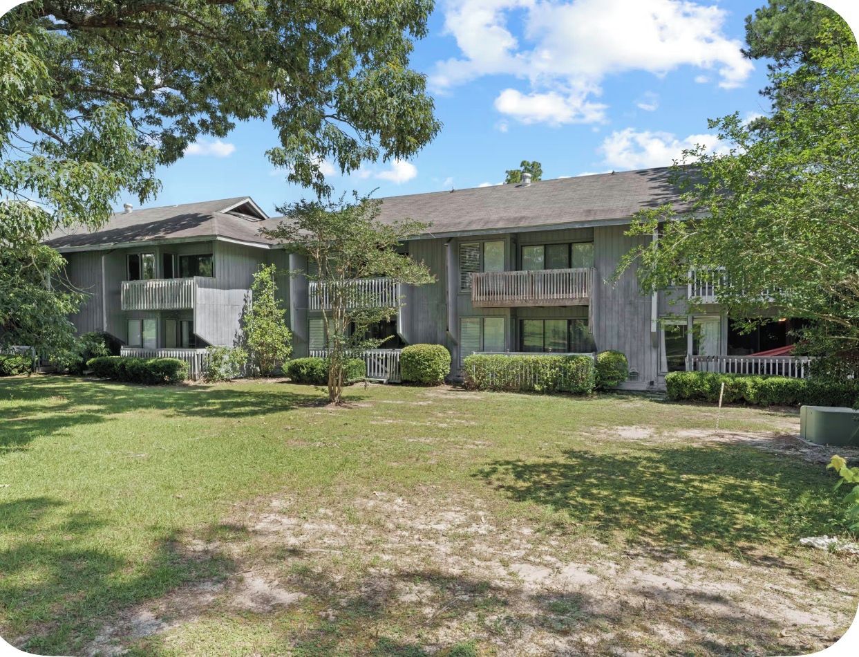 A two-story building with a flat roof, a front porch, and a small front yard.