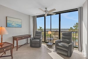 Ein Balkon mit zwei Ledersesseln, einem Tisch, einer Lampe und einem Deckenventilator.
