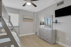 A bedroom with a bed, a dresser, a mirror, a ceiling fan, and a window with blinds. - Beachfront Islands End Condo | Gorgeous Big Carlos Pass Views | Heated Pool + Hot Tub | Free Parking (Fort Myers Beach)