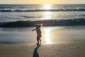A child playing on a beach with waves and sunlight. - Beachfront Islands End Condo | Gorgeous Big Carlos Pass Views | Heated Pool + Hot Tub | Free Parking (Fort Myers Beach)