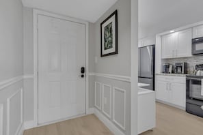 Eine moderne Küche mit weißen Schränken, einem Edelstahl-Kühlschrank und einer Mikrowelle.
