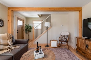 A living room with a sofa, a coffee table, a television, a chair, and a staircase. - The Blue House Hideaway | Less than 20 Minutes to Sugarloaf (Kingfield)
