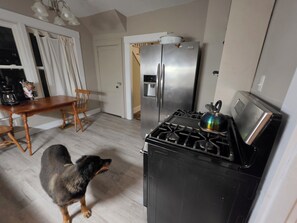 A kitchen with a gas stove, a refrigerator, and a dining table with chairs.
