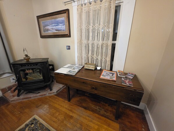 A room with a wooden desk, a framed picture on the wall, and a window with curtains.