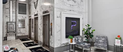 A lobby with marble flooring, a reception desk, a seating area, and a digital display with a 'P' sign.