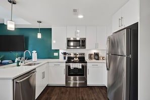 A modern kitchen with stainless steel appliances, white cabinetry, and teal accent walls. - Walk to PayCor : Art Museum : Findlay : Riverfront (Cincinnati)