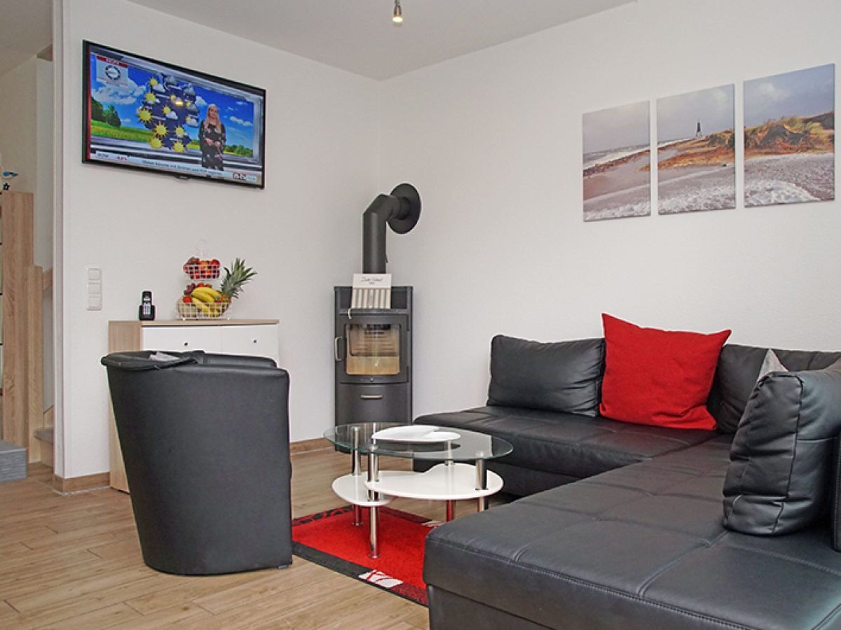 A modern living room with a sofa, a small table, a trash bin, a fireplace, and a television mounted on the wall.