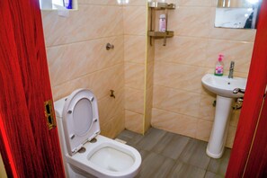 Et lille badeværelse med toilet, vask og spejl.